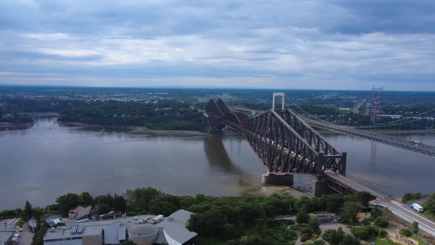 Panoramic aerial view of the Quebec Bridge parallel to the Pierre-Laporte Bridge with their car traffic spanning the St. Lawrence River. Quebec, Canada, 2025.