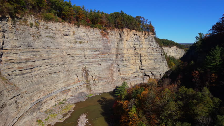 Aerial view of the Genesee River winding through the massive cliffs of Letchworth State Park, New York. The layers of rock and autumn forest colors create a breathtaking natural landscape known as the