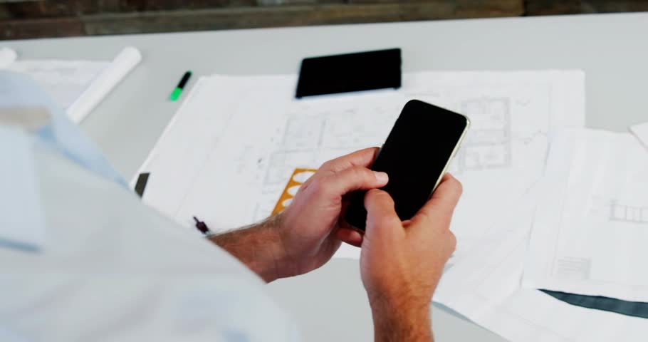 Man picking up smartphone and scrolling while icons drifting and showing engagement above blueprint. Technology, innovation, digital, professional, modern, workspace, creativity