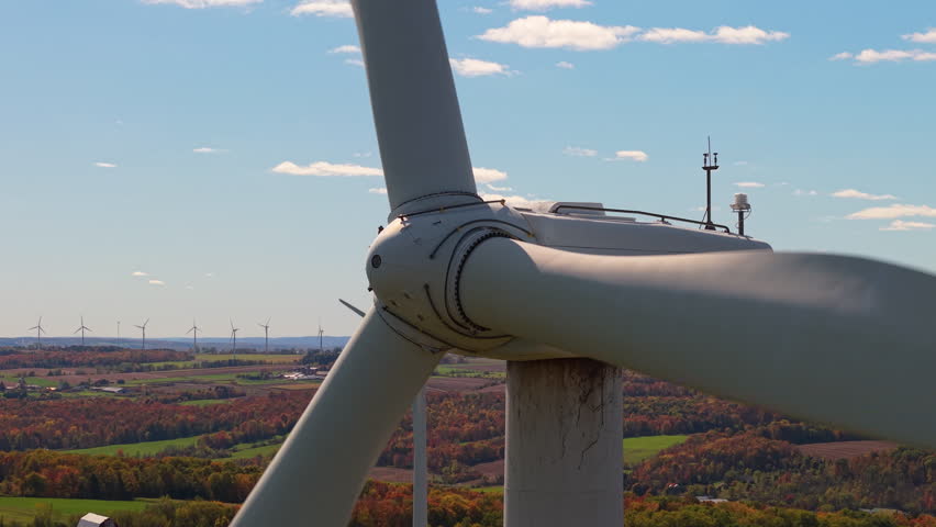 Close-up view of a wind turbine rotor over farmland in upstate New York during autumn, symbolizing renewable energy and sustainability. High quality 4k footage
