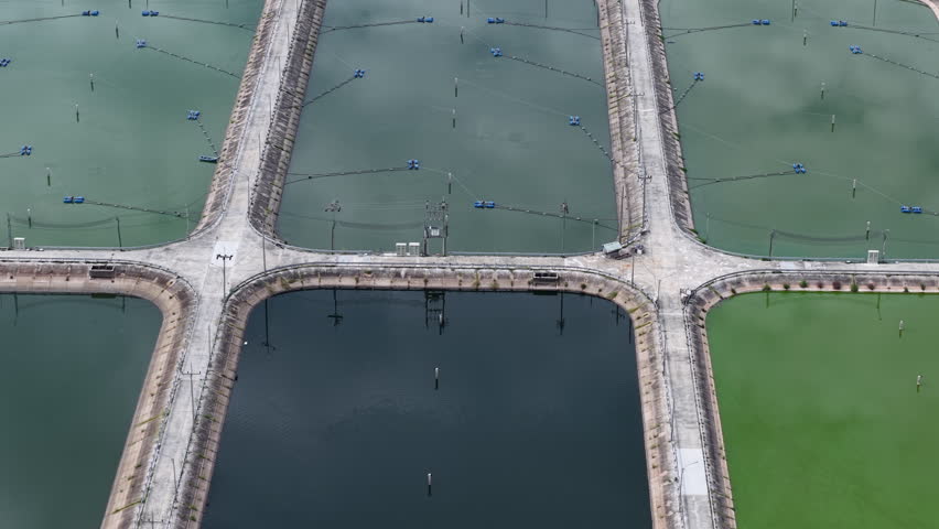 High-angle 4K drone footage shows a systematic arrangement of large, rectangular wastewater lagoons, crucial for industrial water purification and environmental conservation.