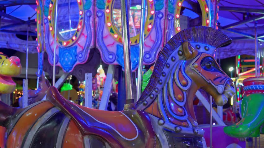 Brightly lit carousel horse at an amusement park spinning during a festive night