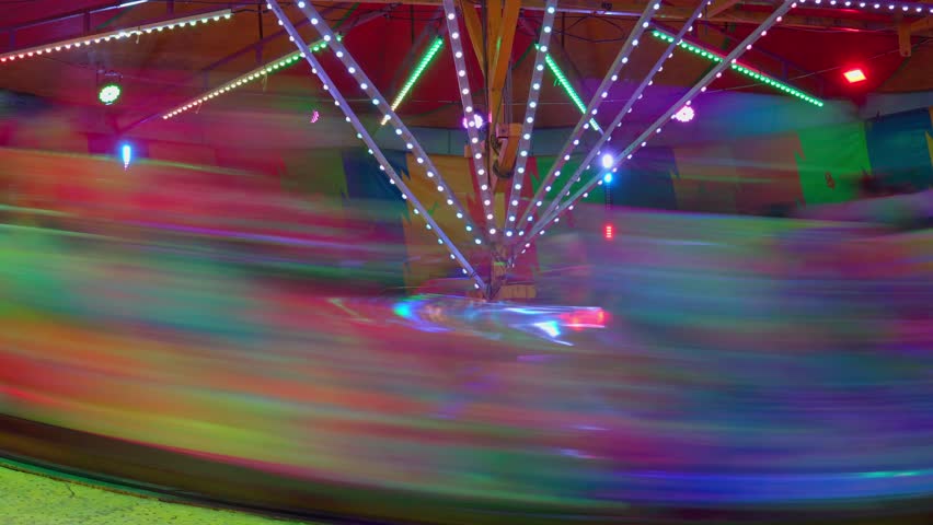 Brightly colored amusement park carousel spinning at night with motion blur creating light streaks