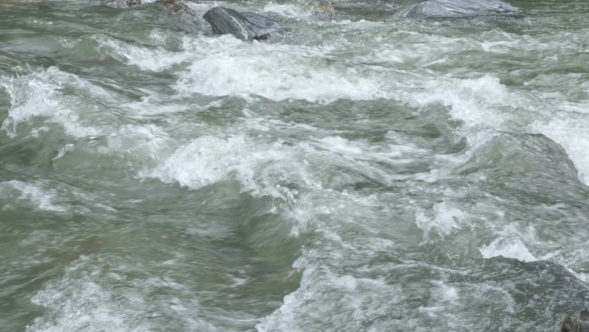 River Flowing With Stone Boulders And Stone Rapids In Haast, New Zealand