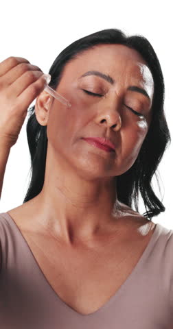 Mature woman, face and dropper with serum in studio for skincare on a white background. Portrait, female person or model with collagen or vitamin c oil for hydration, anti aging or facial treatment