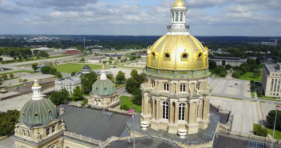 Aerial drone video of the Iowa state capitol building in Des Moines as the camera moves up while tilting down on the golden dome.