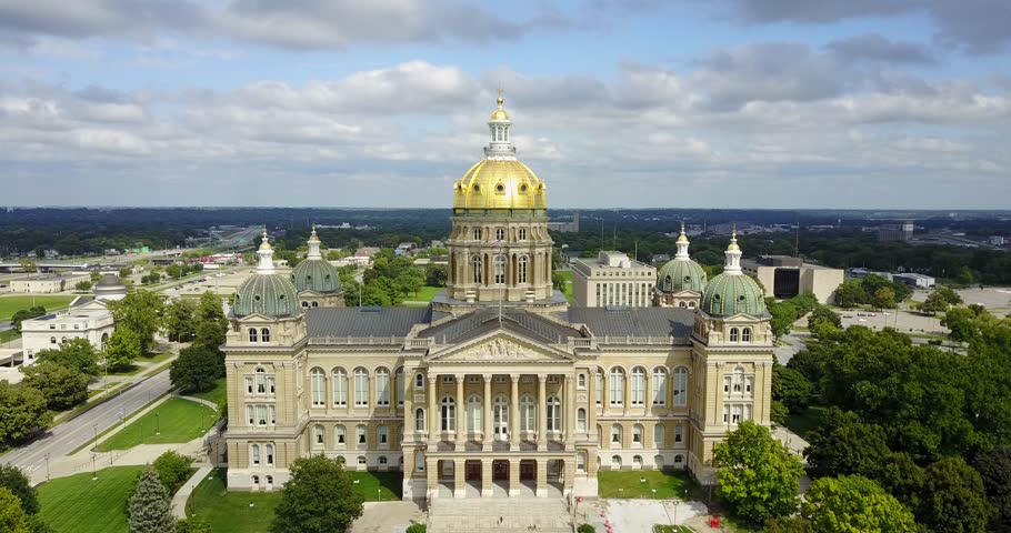 Aerial drone video of the Iowa state capitol building in Des Moines as the camera arcs around it to the right side on a sunny day.