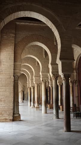 Corridor gallery around inner courtyard of Great Mosque of Kairouan in Tunisia with traditional Islamic arches and columns decorated with Corinthian capitals 