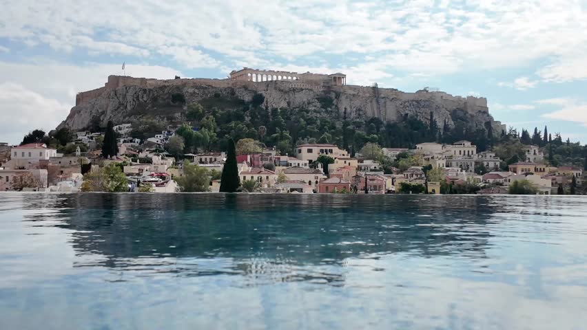 Athens, Beautiful Still frame of Acropolis from a distance over the blue infinity pool under white clouds and blue skies.