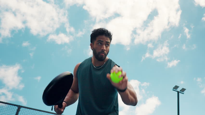 Padel, man and serve ball on court for match practice, skills training and workout fitness. Low angle, blue sky and athlete playing tennis for tournament exercise, sport technique or game performance