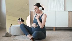 Calm expecting mother sitting in sportswear practicing deep abdominal breathing and meditation to prepare for labor and delivery. Prenatal relaxation and mindfulness concept. - Powered by Shutterstock - Get 15% off with code: PIKWIZARD15