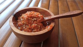 Spicy Indonesian sambal served in a wooden bowl, showing rich red chili texture and traditional culinary style with natural background. - Powered by Shutterstock - Get 15% off with code: PIKWIZARD15