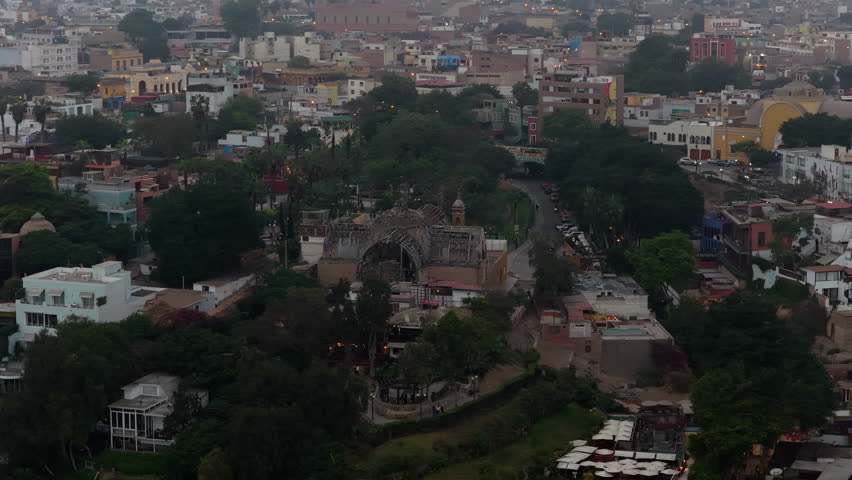 Stunning aerial footage flying over Ermita Church in bohemian Barranco district, Lima, Peru, revealing cityscape at dusk