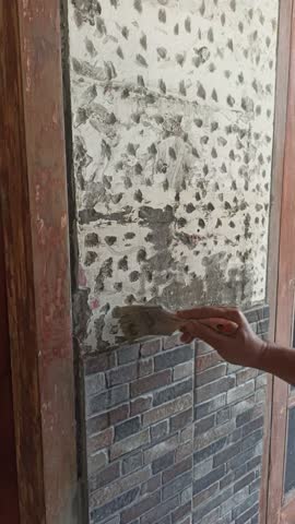 A construction worker installing ceramic tiles on a wall manually, showing craftsmanship, precision, and careful detail in home renovation.