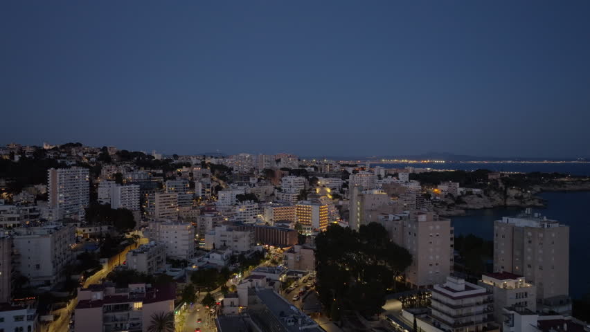 Stunning aerial perspective of the illuminated city of Cala Major in Mallorca, Spain, showing beautiful coastline and urban lights
