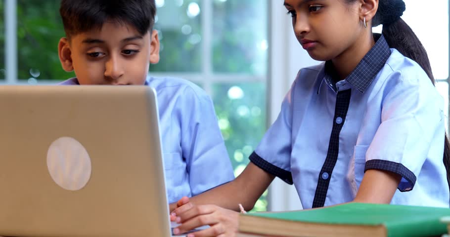 Indian School Kids Studying Together on Laptop in Classroom While Wearing School Uniforms, Group Learning, Sharing Knowledge, Collaborating on Academic Tasks Using Technology During Education Session