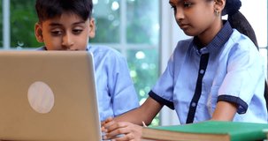 Indian School Kids Studying Together on Laptop in Classroom While Wearing School Uniforms, Group Learning, Sharing Knowledge, Collaborating on Academic Tasks Using Technology During Education Session - Powered by Shutterstock - Get 15% off with code: PIKWIZARD15