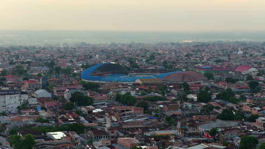 Panoramic aerial view of the city of Iquitos, located in the peruvian Amazon jungle. Hazy urban skyline at sunset with Max Augustin stadium