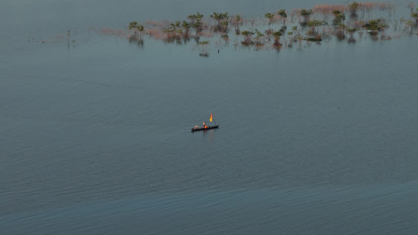 Aerial view of people in a canoe kayaking on the Amazon river. Boat moving through calm blue waters in the rainforest