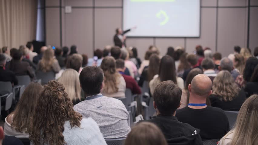 Corporate training session, speaker engaging business audience discussing workplace topics.