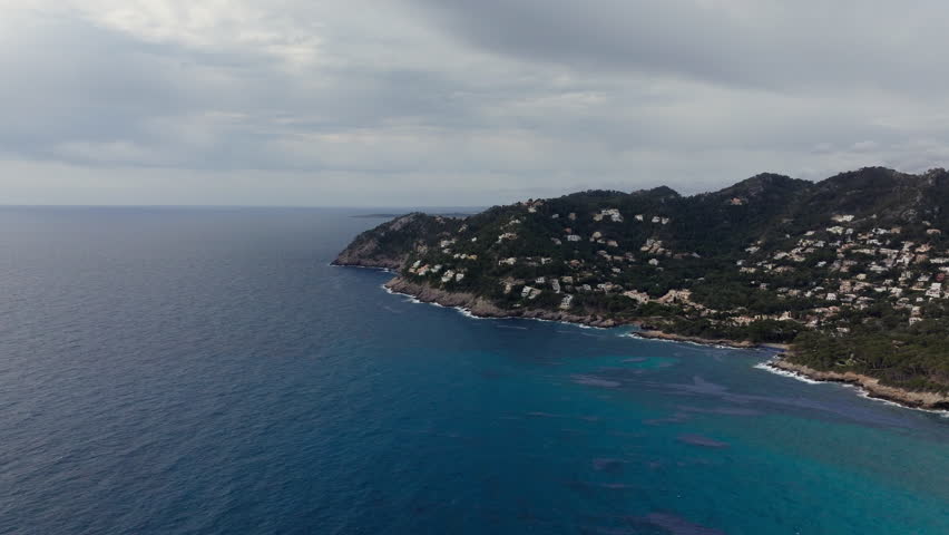 Aerial footage showcasing stunning coastal landscape of Mallorca, Spain, featuring clear turquoise water and cliffside villas
