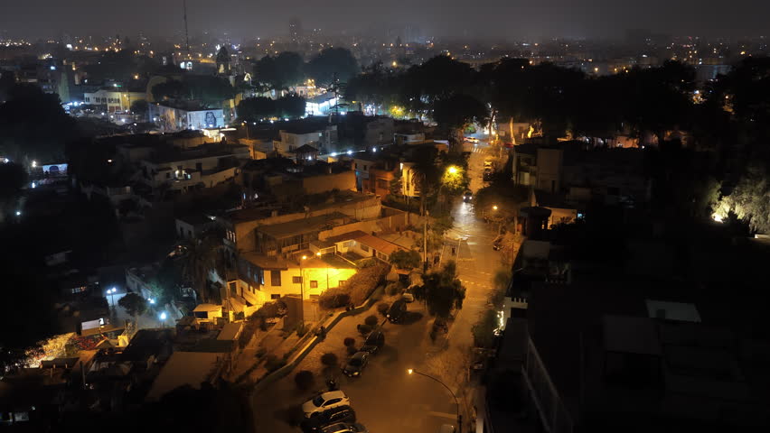 Foggy night aerial view of Lima, Peru. Capital city's urban landscape with illuminated streets, moving cars and building lights
