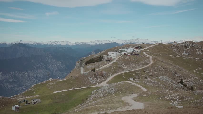 Aerial drone view of Schilthorn summit with winding mountain trails, rugged alpine terrain, and snowy peaks in background creating stunning Bernese Alps scenery under clear sky