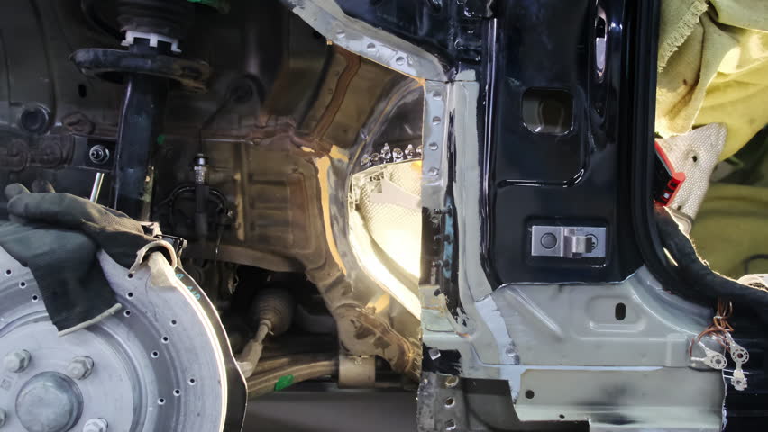 Broken car without tire and glowing lamp in repair workshop closeup. Maintaining automobile on hydraulic lift platform at service station