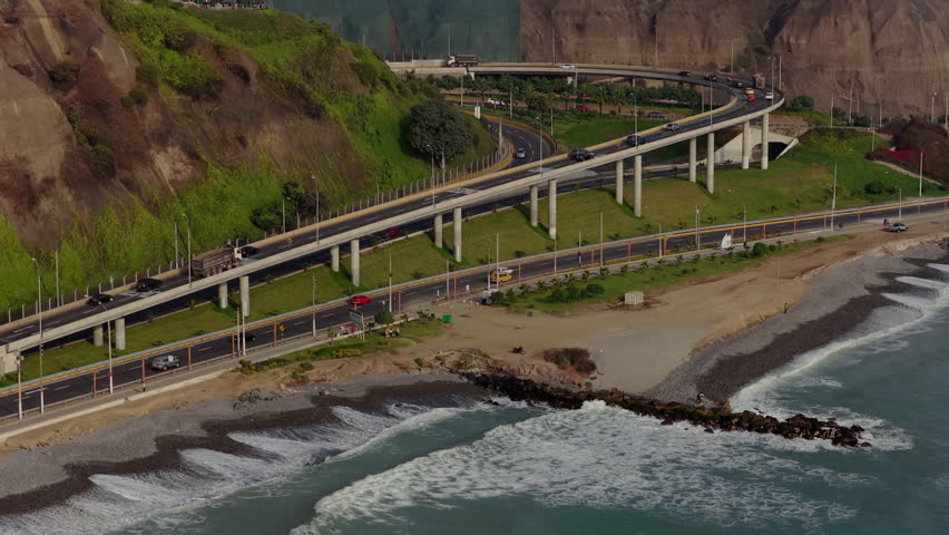 Aerial view of Circuito de Playas highway as vehicles cruise along the coast of Pacific Ocean and its shoreline in Lima, Peru