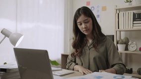 Professional young Asian female business accountant sitting using a calculator and a laptop computer for analyzing financial data at her desk in the office. Businesswoman working in her workplace.  - Powered by Shutterstock - Get 15% off with code: PIKWIZARD15