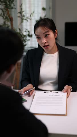 Professional real estate agent explains a contract to her client, pointing to important clauses and details about the property purchase agreement.