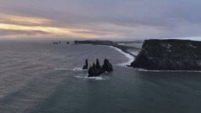 Aerial view of basalt sea stacks rising from the ocean near black sand Reynisfjara beach, with the sun rising in Iceland, Iceland. - Powered by Shutterstock - Get 15% off with code: PIKWIZARD15