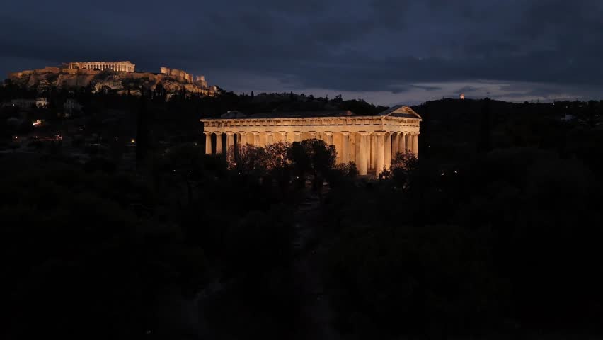 Athens,Aerial view forward towards iconic Hephaestus Temple,one of the most well preserved in Greece and Acropolis hill at the background,both beautifully illuminated.