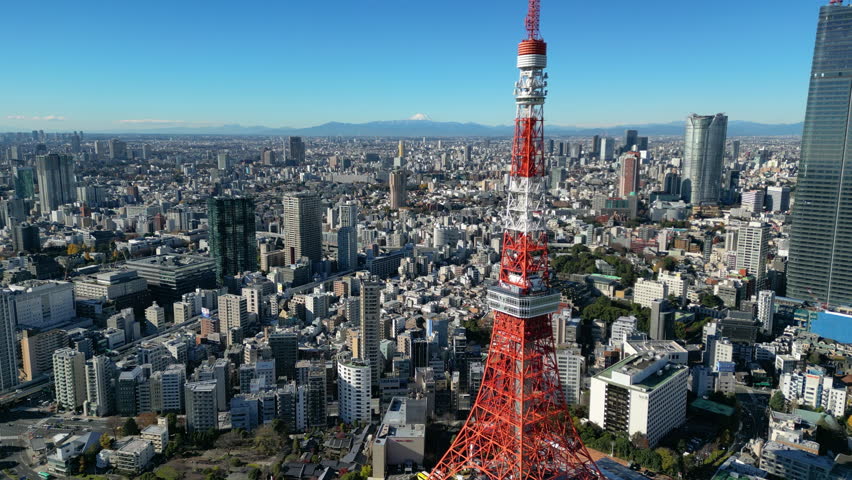 Aerial view passing the Tokyo tower overlooking the cityscape, sunny day in Japan