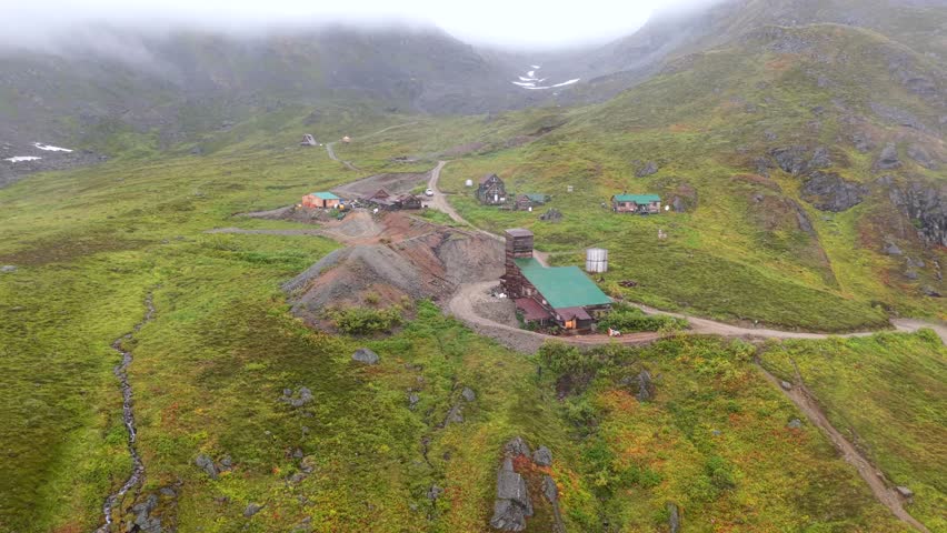Aerial view of buildings nestled in green land, a rugged landscape under a misty sky, Palmer, Alaska, United States.