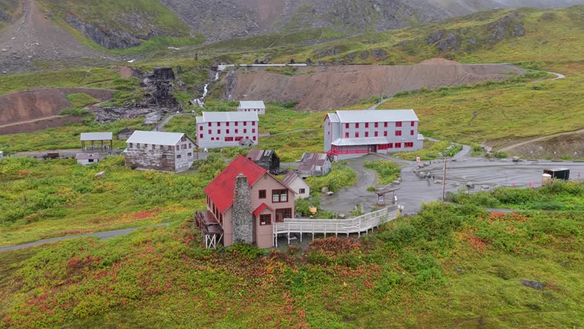 Aerial view of the historic Independence Mine buildings nestled amongst vibrant green and red vegetation, Palmer, Alaska, United States.