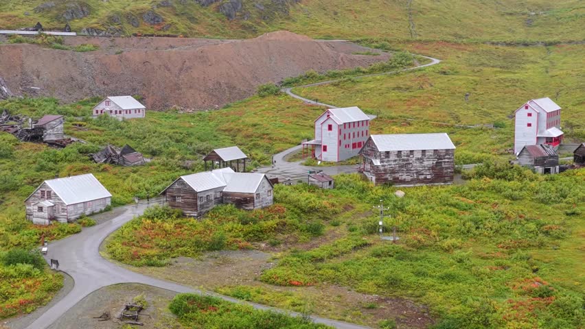 Aerial view of the abandoned buildings, with red and white accents, nestled amongst the lush green landscape, Palmer, Alaska, United States.