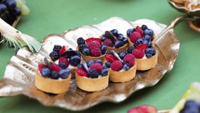 Delicious display of mini fruit tarts adorned with fresh berries and cream, presented on elegant golden platter. Indulgent sweet treats evoke joy, happiness, and satisfaction. - Powered by Shutterstock - Get 15% off with code: PIKWIZARD15