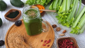 Freshly made green smoothie in a glass jar, surrounded by healthy ingredients like celery, avocado, goji berries, flax seeds, and spirulina, representing a nutritious and detoxifying diet - Powered by Shutterstock - Get 15% off with code: PIKWIZARD15