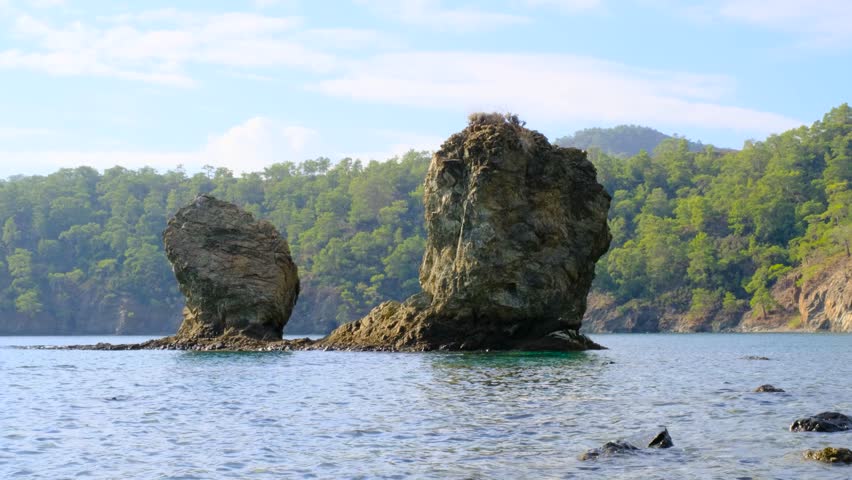 Beautiful coastal scenery with sea, rocks, and forest. Tranquil seaside landscape with rocky islets and trees. Coastal rocks and forest landscape by the sea.