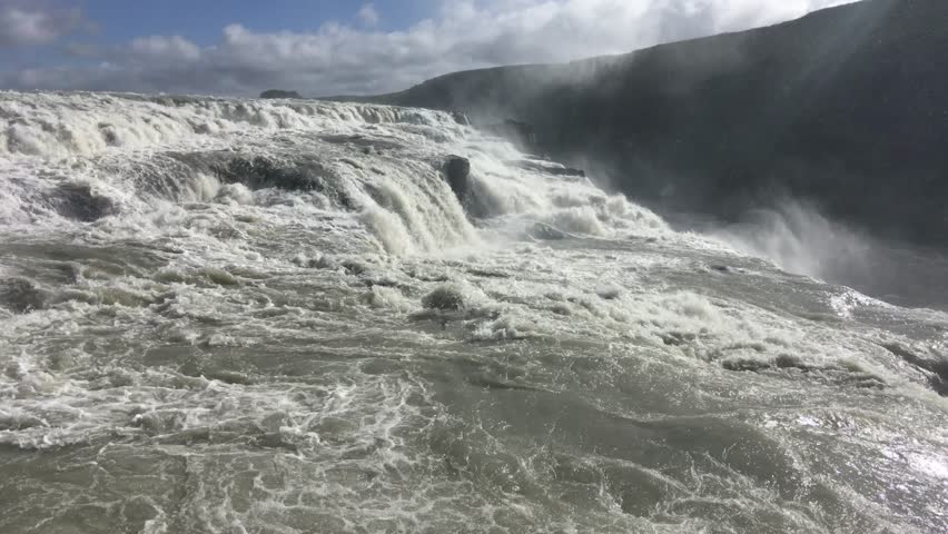 Powerful river rapids cascading over rocks in a dramatic landscape, the churning water creates a mesmerizing display of nature