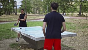 Friends engage in a friendly game of table tennis outdoors in a park. They are enjoying leisure time, staying active, and having fun together, showcasing recreational sports and outdoor activities. - Powered by Shutterstock - Get 15% off with code: PIKWIZARD15