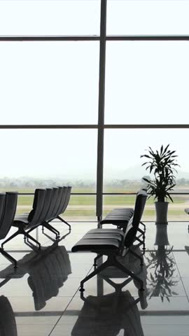 Quiet airport terminal waiting area with empty seats and reflections on the polished floor, overlooking the runway through a large window on a tranquil day, evoking a sense of calm travel