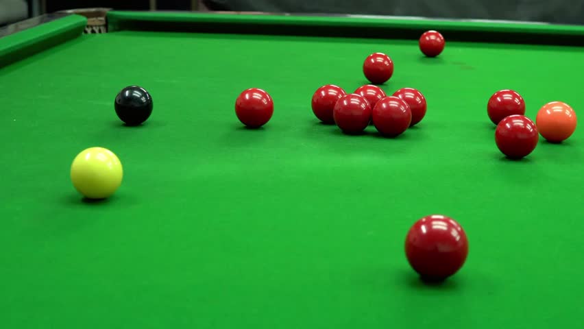 Snooker balls scattered on a green snooker table ready for a competitive game
