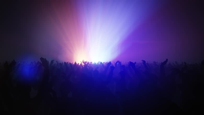 Energetic crowd at a music concert with hands raised towards the stage lights.