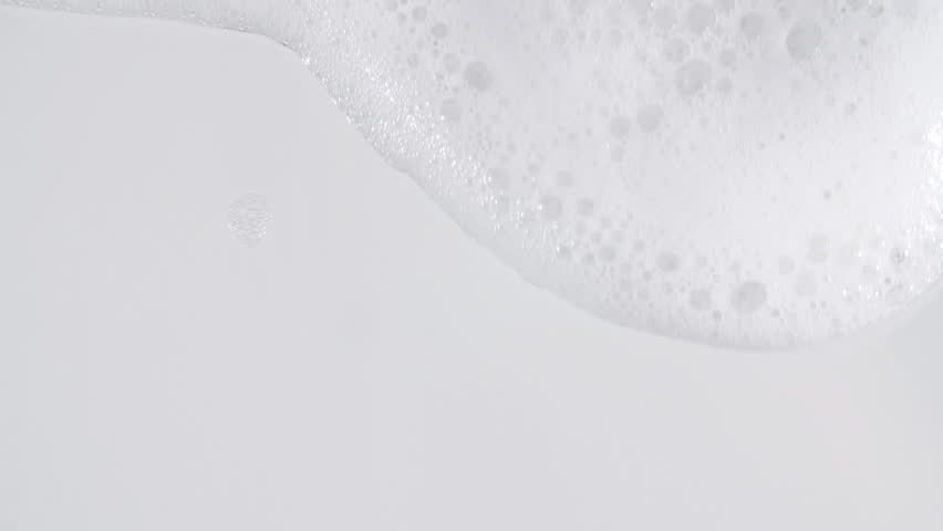 Bubbles of white soap foam. Moving Soap foam popping bubble on a white backdrop. Soap sud macro structure. Clean, cleaning concept, laundry, shower. 