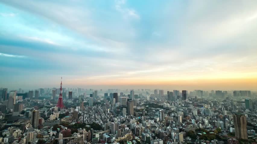 Aerial view of Tokyo cityscape with Tokyo Tower under a cloudy blue sky at dusk