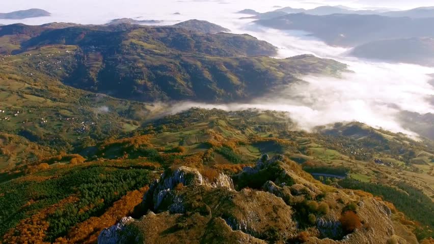 Aerial view of a scenic mountain landscape with clouds and autumn foliage colors