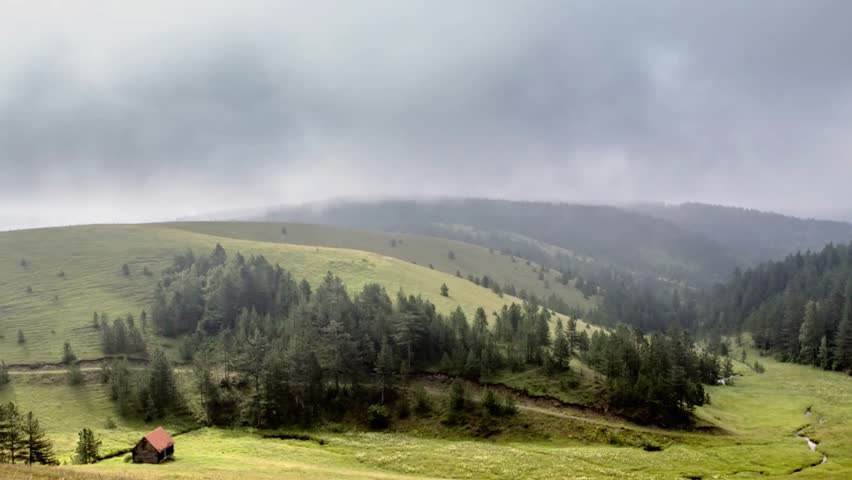 Serene mountain landscape with rolling hills and a small cabin under cloudy skies