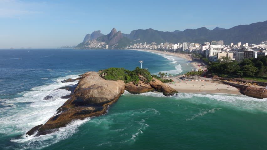Aerial orbiting shot of Pedra do Arpoador and Ipanema Beach on a sunny day in Rio de Janeiro, Brazil.